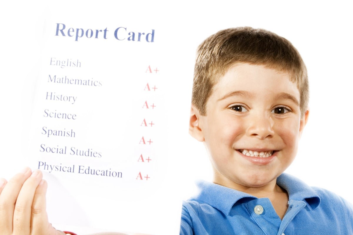 boy holding a report card with A's